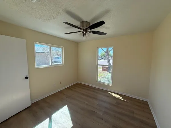 a view of empty room with wooden floor and fan
