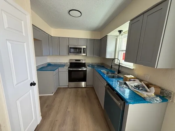 a kitchen with kitchen island granite countertop a sink a counter top space stainless steel appliances and cabinets