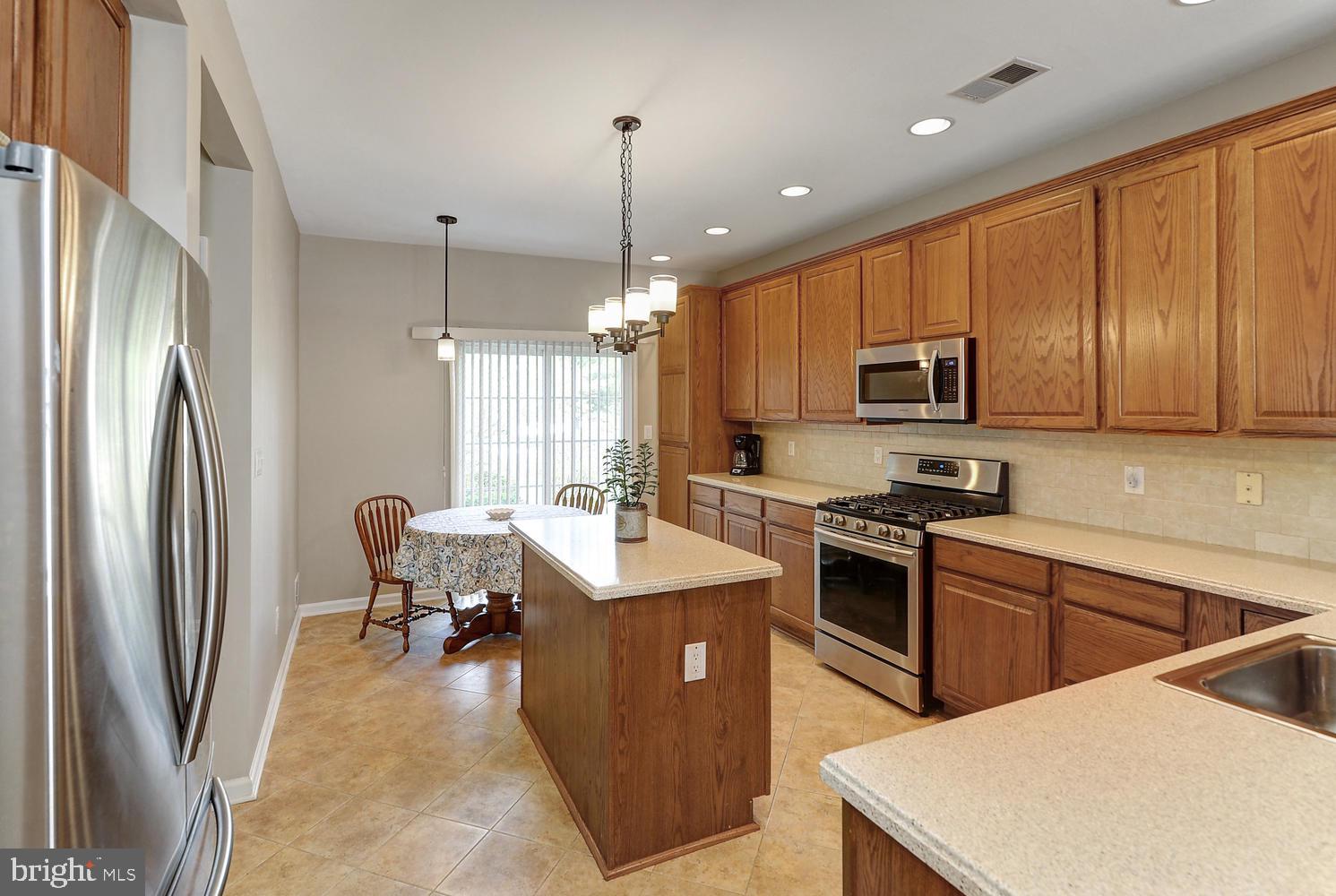 17 Windsor Pond Road Princeton Junction, NJ 08550 - Photo 11 of 20 a kitchen with stainless steel appliances granite countertop a refrigerator a stove top oven a sink dishwasher a dining table and chairs with wooden floor