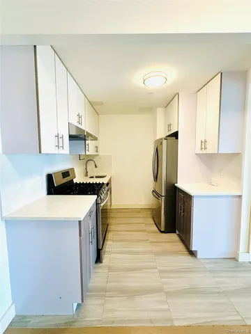 a large white kitchen with a refrigerator a stove top oven and a sink
