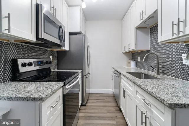 a kitchen with stainless steel appliances granite countertop a sink stove and cabinets