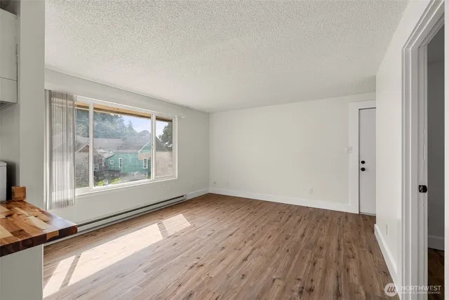 a view of an empty room with wooden floor and a window