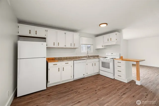 a kitchen with cabinets appliances wooden floor and a window