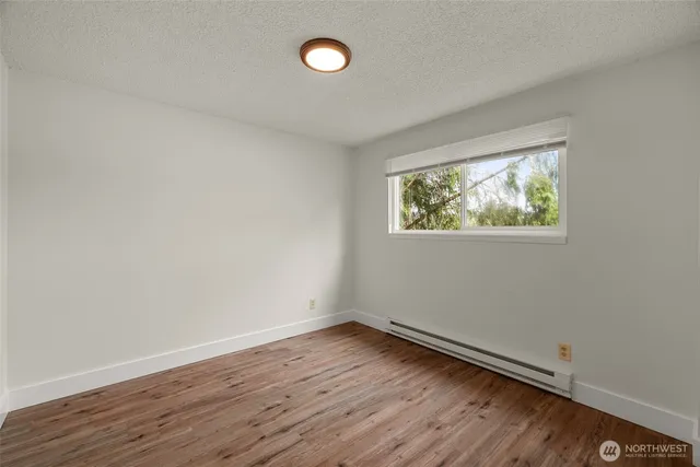 an empty room with wooden floor and window