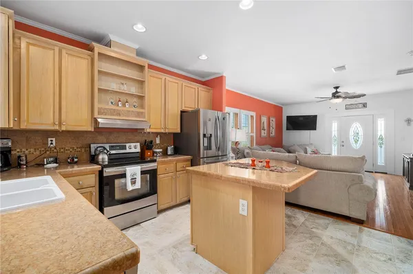 a open kitchen with stainless steel appliances granite countertop a stove top oven a sink dishwasher and white cabinets with wooden floor