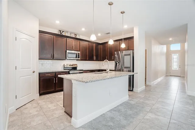 a kitchen with kitchen island granite countertop a stove a sink a refrigerator and a oven