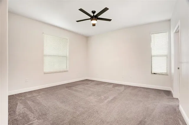 an empty room with window and a ceiling fan