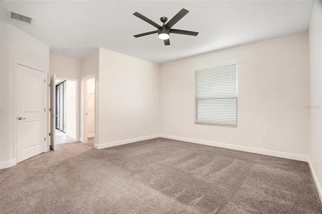 an empty room with a ceiling fan and window