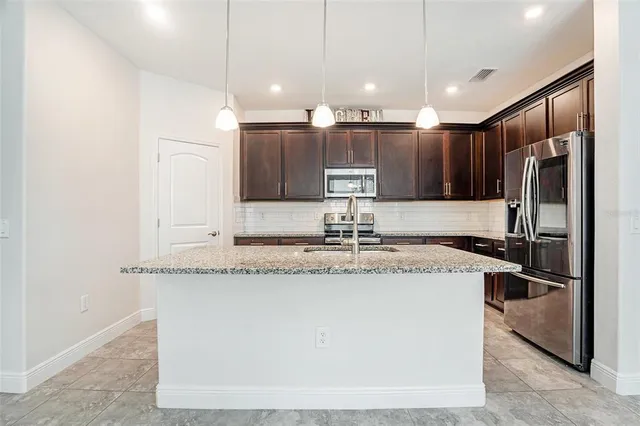 a kitchen with stainless steel appliances granite countertop a sink and a refrigerator