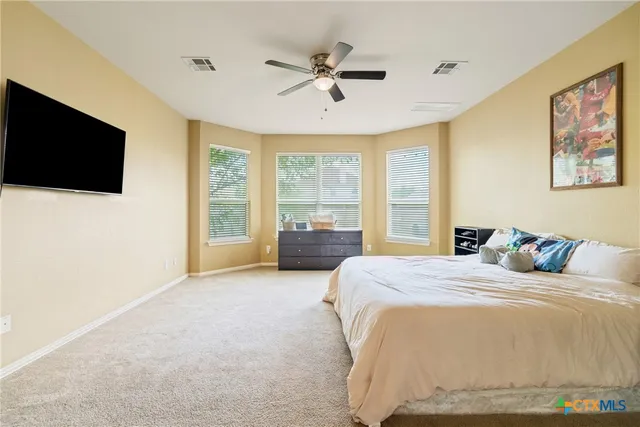 a bedroom with a large bed and a flat tv screen on dresser