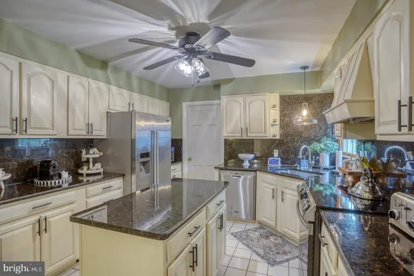 a kitchen with stainless steel appliances granite countertop a sink a stove cabinets and living room view