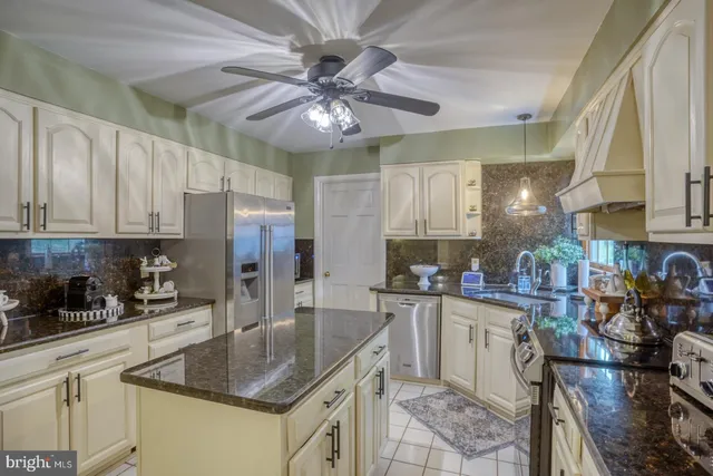 a kitchen with stainless steel appliances granite countertop a sink a stove cabinets and living room view