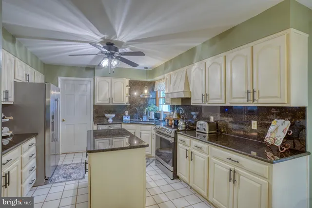 a kitchen with stainless steel appliances granite countertop a sink a stove a refrigerator a washer dryer and cabinets