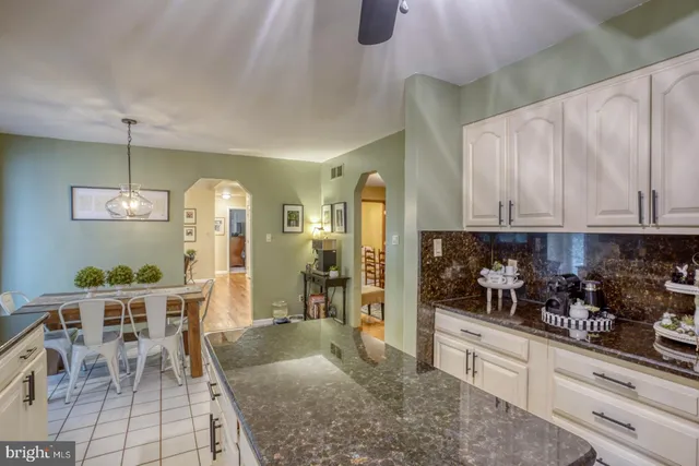 a kitchen with stainless steel appliances kitchen island granite countertop dining table chairs and a refrigerator