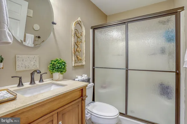 a bathroom with a granite countertop shower sink vanity mirror and toilet