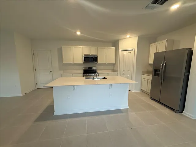 a large kitchen with stainless steel appliances a refrigerator a sink a stove a microwave a counter top and oven