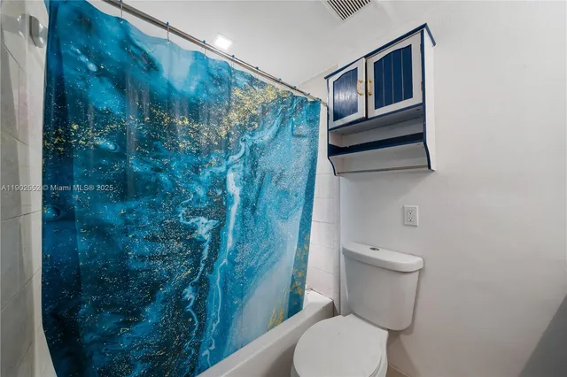 a white toilet sitting next to a shower curtain
