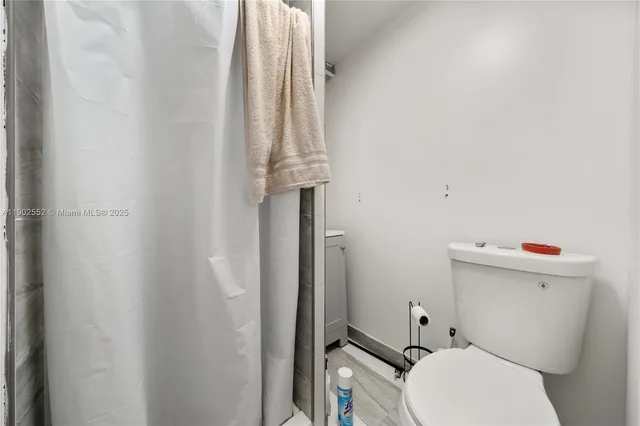 a white toilet sitting next to a shower curtain