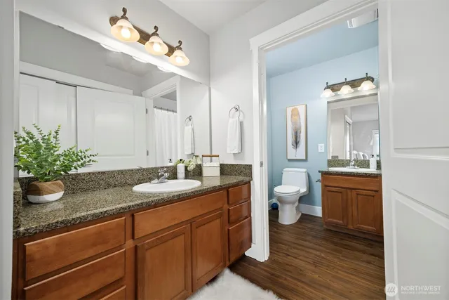 a bathroom with a granite countertop sink a toilet and mirror