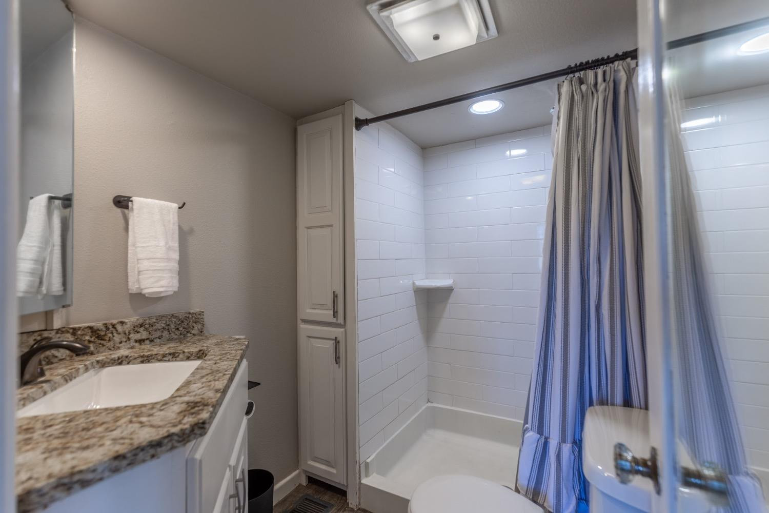 2124 Broadway Street Lubbock, TX 79401 - Photo 13 of 14 a bathroom with a granite countertop sink a toilet and shower