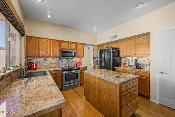 a kitchen with stainless steel appliances granite countertop a stove refrigerator and a sink
