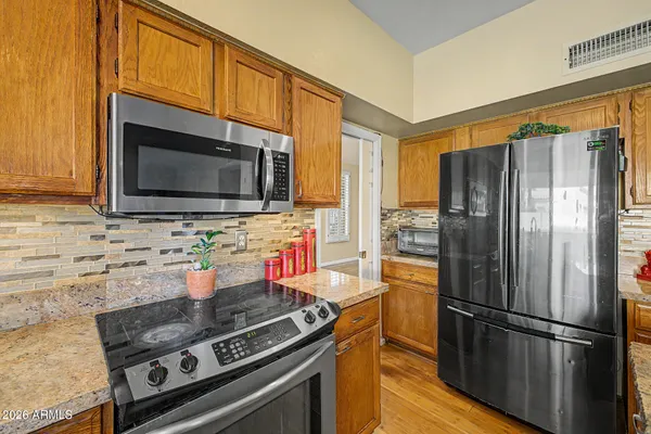 a kitchen with stainless steel appliances granite countertop a stove microwave refrigerator and cabinets
