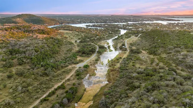 an aerial view of residential house with outdoor space and trees all around