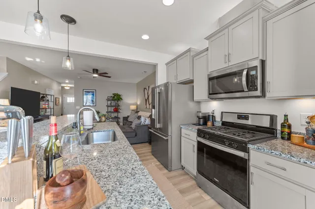 a kitchen with stainless steel appliances kitchen island granite countertop a stove refrigerator and cabinets