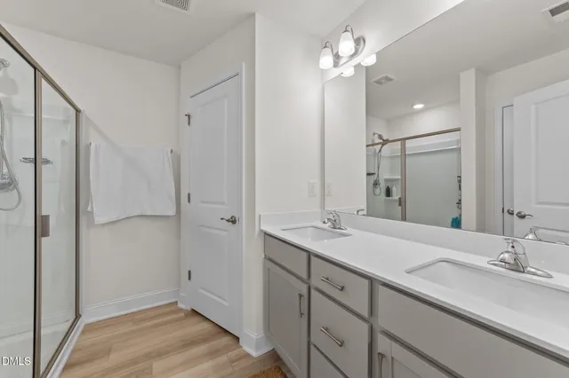 a bathroom with a double vanity sink mirror and shower