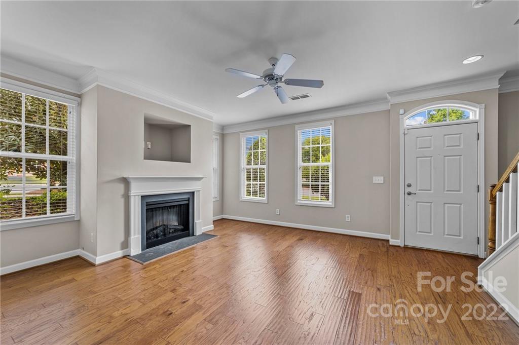 10559 Rocky Ford Club Road Charlotte, NC 28078 - Photo 3 of 18 an empty room with windows fireplace and wooden floor