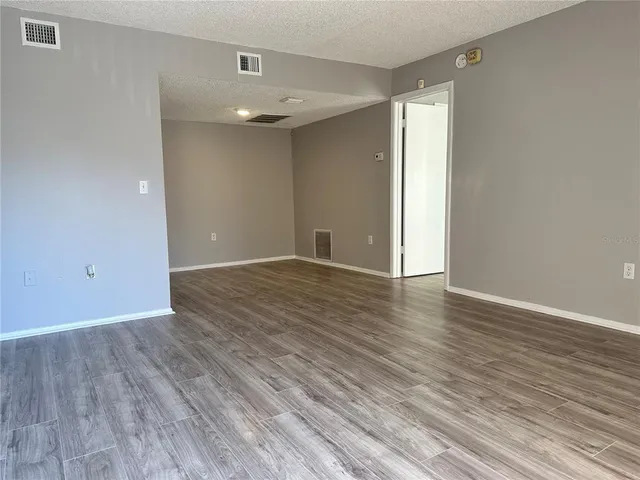 a view of an empty room with wooden floor