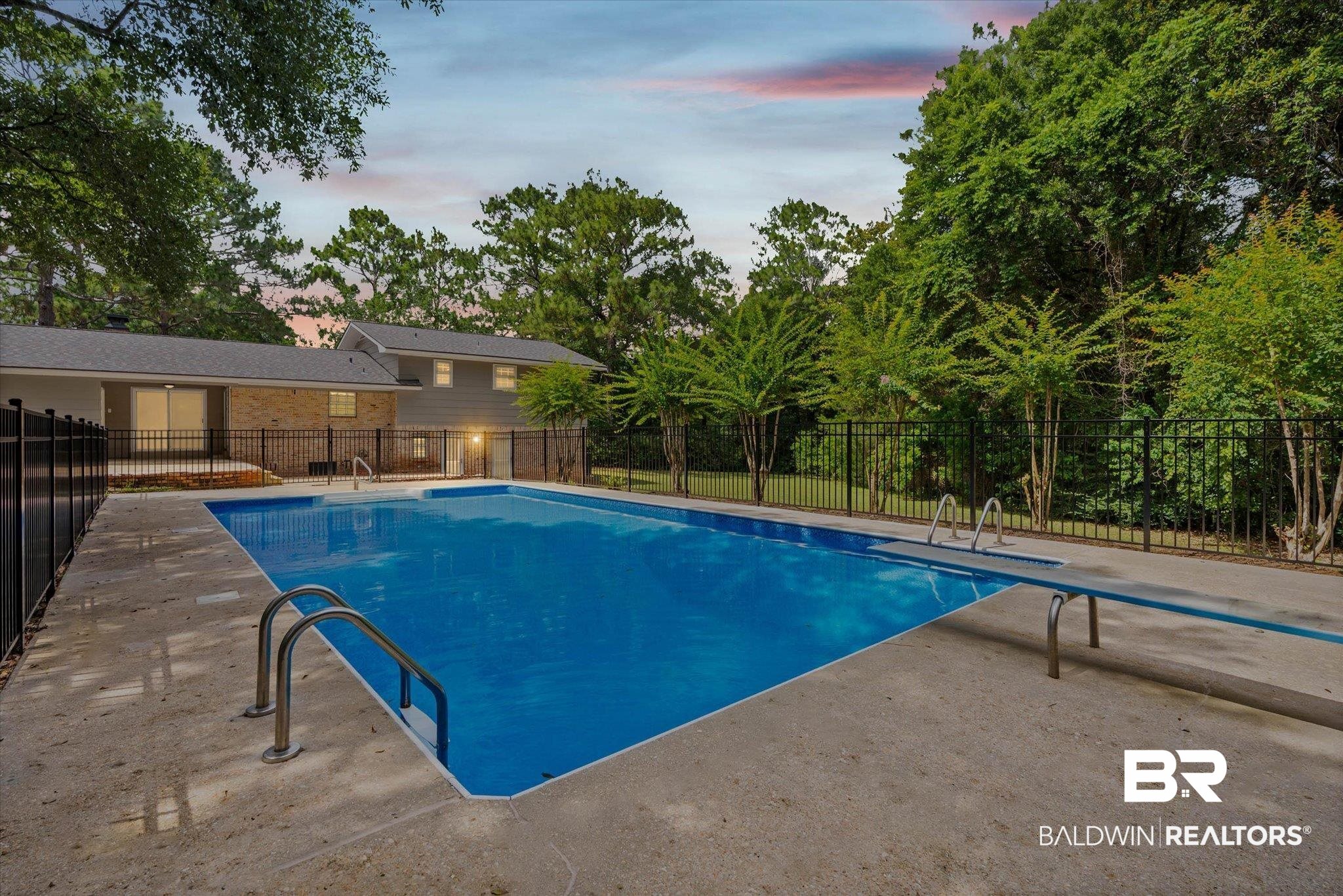 8301 Fordham Road Mobile, AL 36619 - Photo 2 of 57 Expansive backyard featuring a large swimming pool, concrete decking, black metal fencing, and mature trees