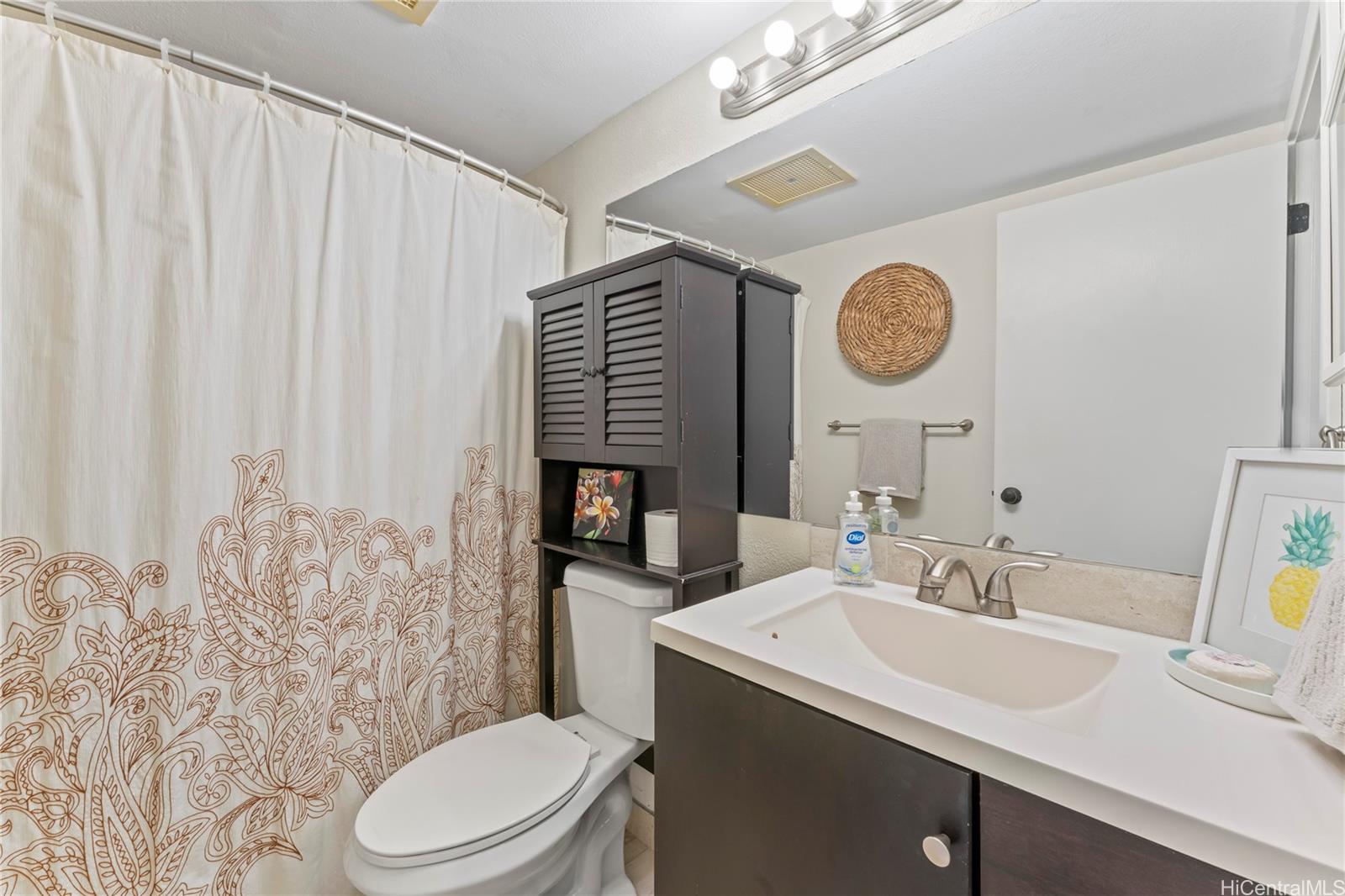 92-1136 Hame Street, Unit 10102 Kapolei, HI 96707 - Photo 19 of 22 a bathroom with a sink a toilet and a mirror