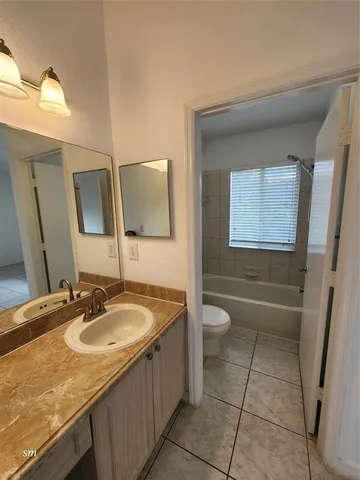 a bathroom with a granite countertop sink a toilet and a mirror