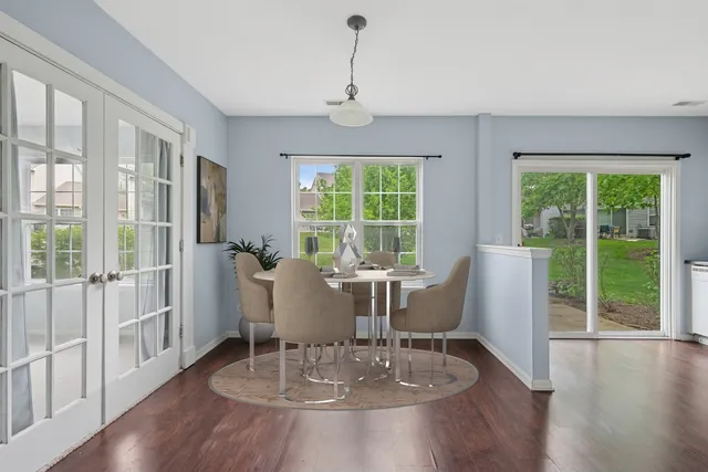 a dining room with wooden floor a chandelier a glass table and chairs