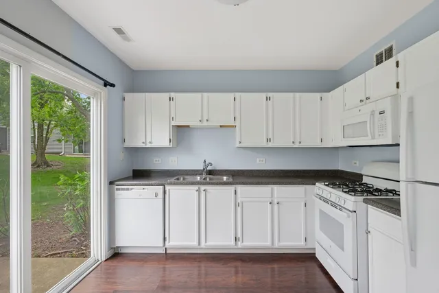 a kitchen with granite countertop white cabinets and white appliances