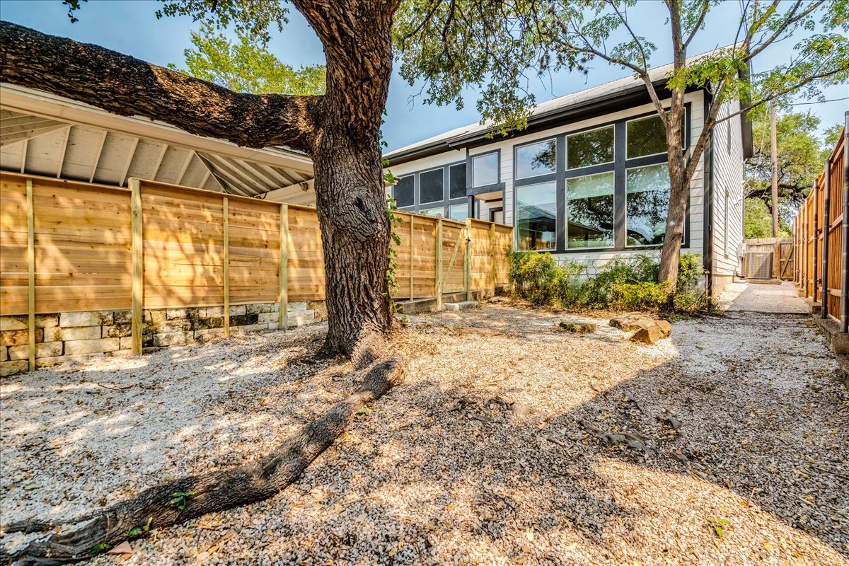 2811 Hardeman Street, Unit B Austin, TX 78704 - Photo 30 of 34 Mature trees shade a private gravel yard enclosed by wood fencing along the home exterior.