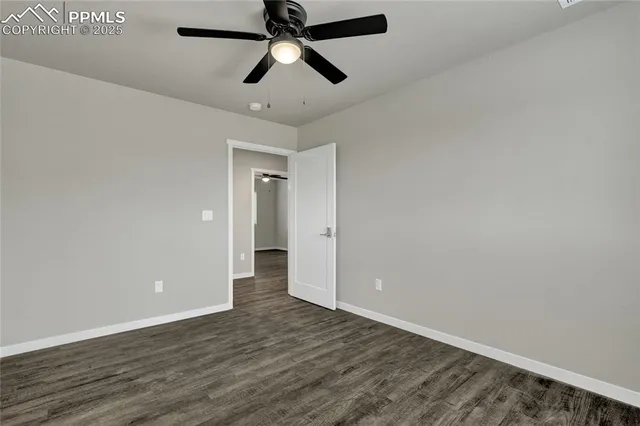 an empty room with wooden floor and ceiling fan