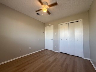 2202 Donahue Lane, Unit B Austin, TX 78744 - Photo 12 of 16 Unfurnished bedroom featuring a textured ceiling, dark wood-style floors, a ceiling fan, and a closet