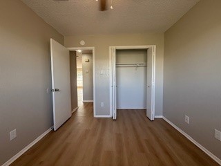 2202 Donahue Lane, Unit B Austin, TX 78744 - Photo 14 of 16 Unfurnished bedroom featuring a textured ceiling, dark wood-type flooring, a closet, and ceiling fan