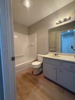 2202 Donahue Lane, Unit B Austin, TX 78744 - Photo 16 of 16 Bathroom featuring a textured ceiling, vanity, light wood-style flooring, shower / bath combination, and a textured wall