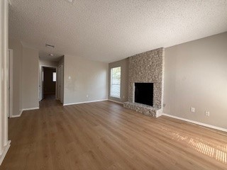 2202 Donahue Lane, Unit B Austin, TX 78744 - Photo 2 of 16 Unfurnished living room with a textured ceiling, a large fireplace, and wood finished floors