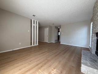 2202 Donahue Lane, Unit B Austin, TX 78744 - Photo 3 of 16 Unfurnished living room with a fireplace, wood finished floors, and a textured ceiling