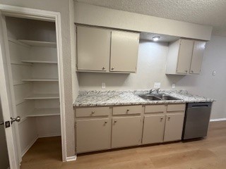 2202 Donahue Lane, Unit B Austin, TX 78744 - Photo 7 of 16 Kitchen featuring light countertops, a textured ceiling, light wood-style floors, and dishwasher