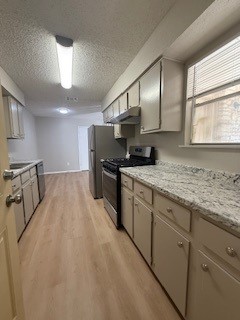 2202 Donahue Lane, Unit B Austin, TX 78744 - Photo 8 of 16 Kitchen featuring a textured ceiling, stainless steel range oven, light wood-style flooring, and under cabinet range hood