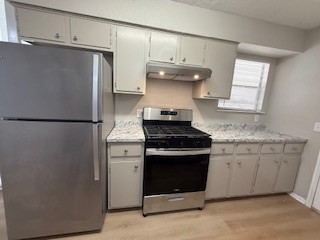 2202 Donahue Lane, Unit B Austin, TX 78744 - Photo 9 of 16 Kitchen featuring appliances with stainless steel finishes, light wood-style flooring, under cabinet range hood, a textured ceiling, and gray cabinets