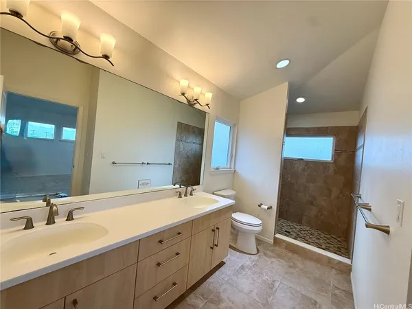a spacious bathroom with double sink a toilet a shower and a large mirror