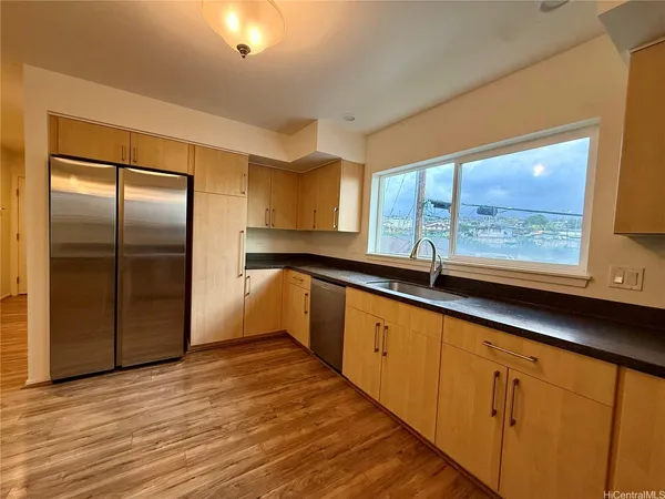 a large kitchen with kitchen island a large window a sink and stainless steel appliances