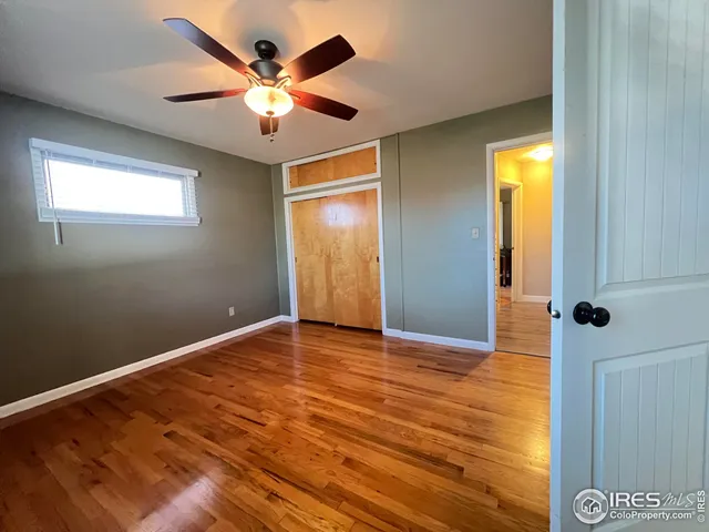 an empty room with wooden floor fan and windows