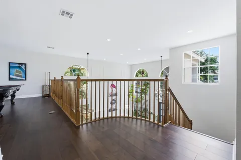 a view of a hallway with wooden floor and windows